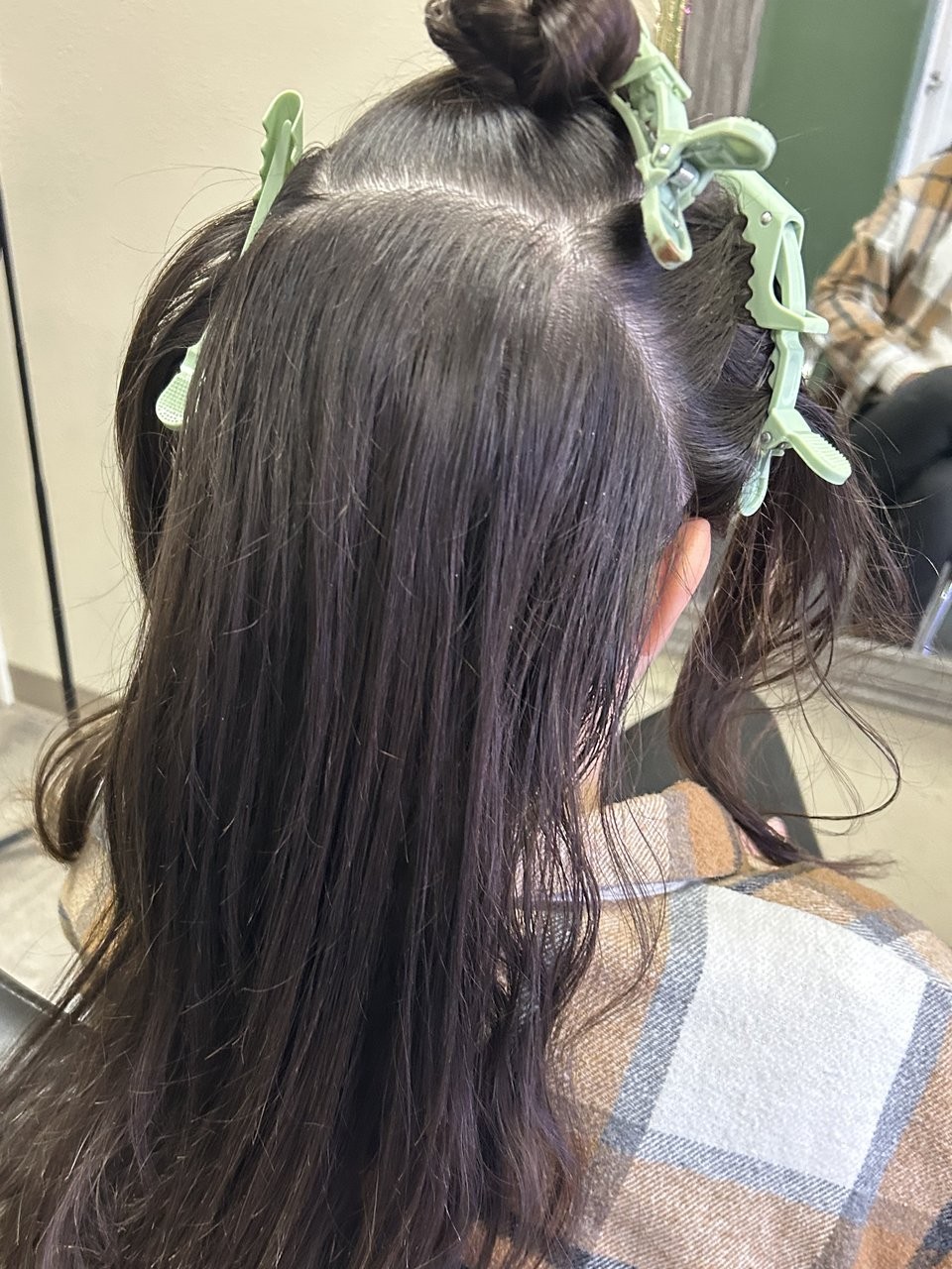 Before: dark hair parted and held in green sectioning clips in the salon chair.